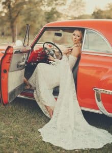 red classic car with a bride in the driver's seat.